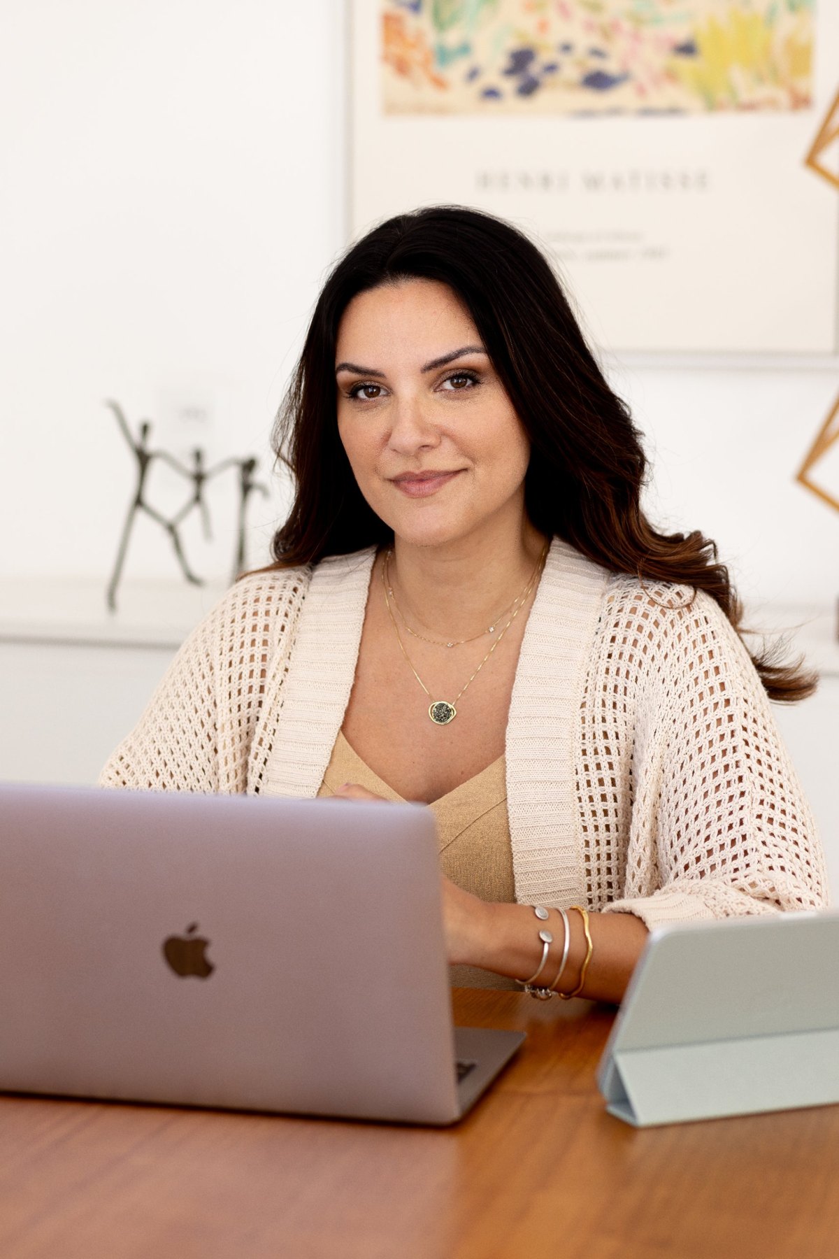 Vivian Dornellas à mesa de trabalho, com um quadro de Henri Matisse e uma escultura de três figuras ao fundo